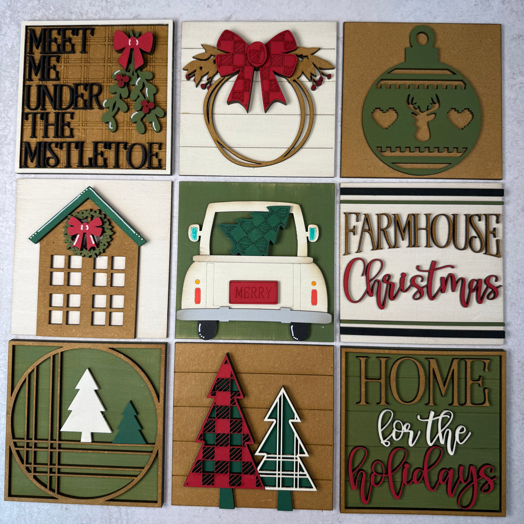 A 3x3 grid of nine handmade wooden Christmas sign cards with various holiday designs including a wreath, ornament, house, truck, trees, and text messages like 'Meet Me Under The Mistletoe' and 'Home for the Holidays'.